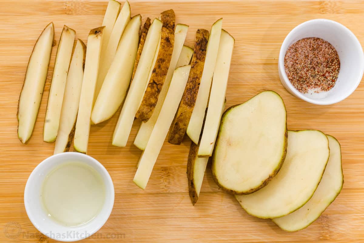 Sliced spuds on a cutting board with seasoning and oil
