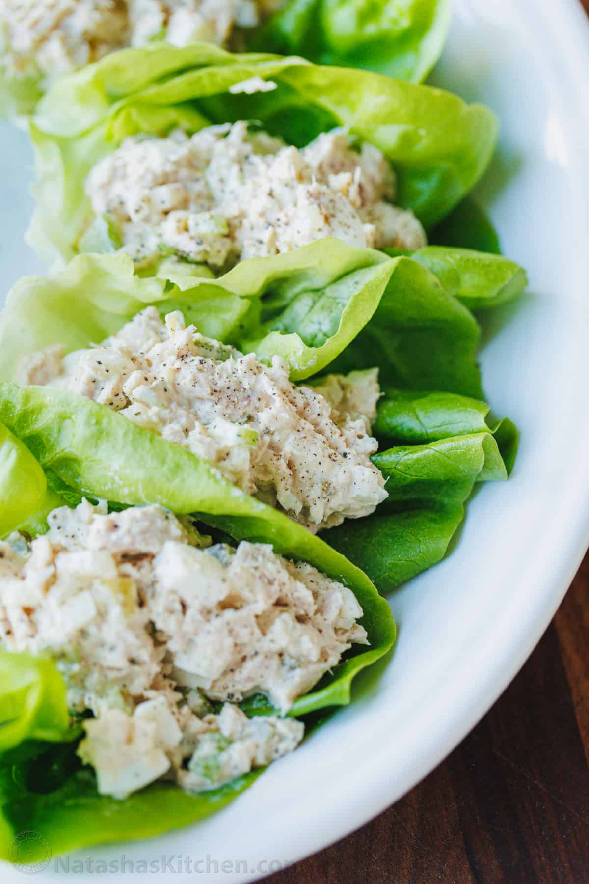 This Classic Tuna Salad recipe is light and fresh, made with tuna, celery, eggs, and the best tuna salad dressing. Great for meal prep lunch! Tuna Salad served over lettuce cups on a white plate with pepper on top