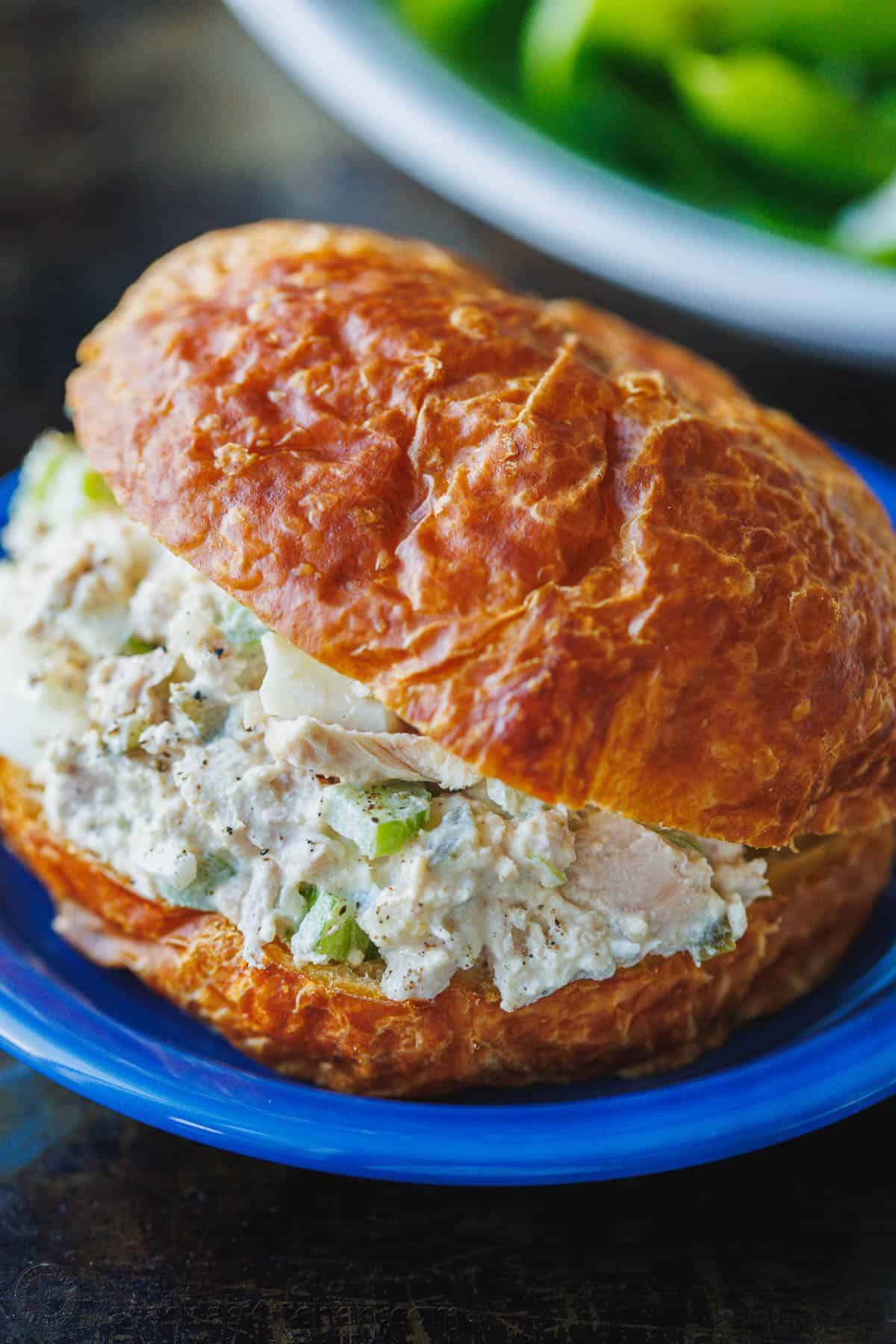 This Classic Tuna Salad recipe is light and fresh, made with tuna, celery, eggs, and the best tuna salad dressing. Great for meal prep lunch! Tuna Salad served in a croissant on a blue plate